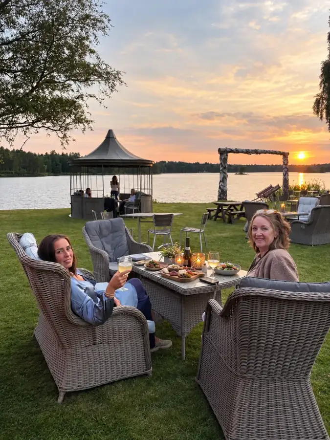 Guests sharing dinner by Lake Skagern at sunset