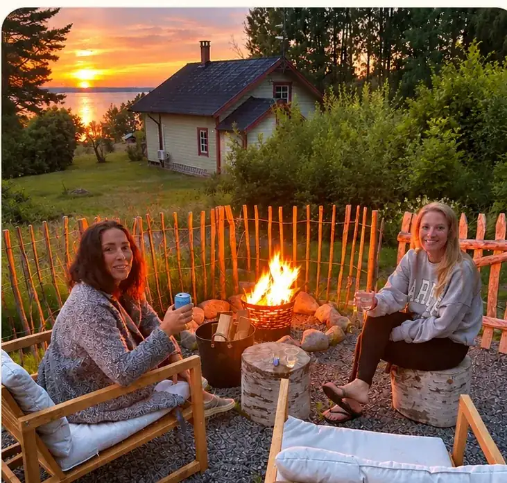 Two women gathering around the fire at sunset at Tree of Life Sweden